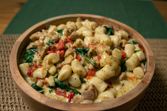 Bowl of creamy low FODMAP mushroom and spinach gnocchi with herbs.